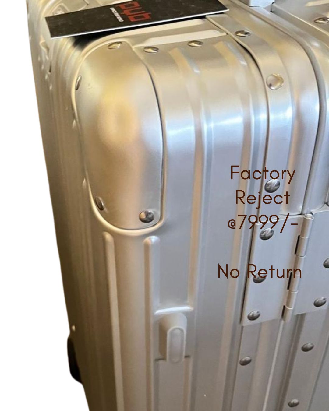 Silver suitcase labeled 'Factory Reject' on a white background